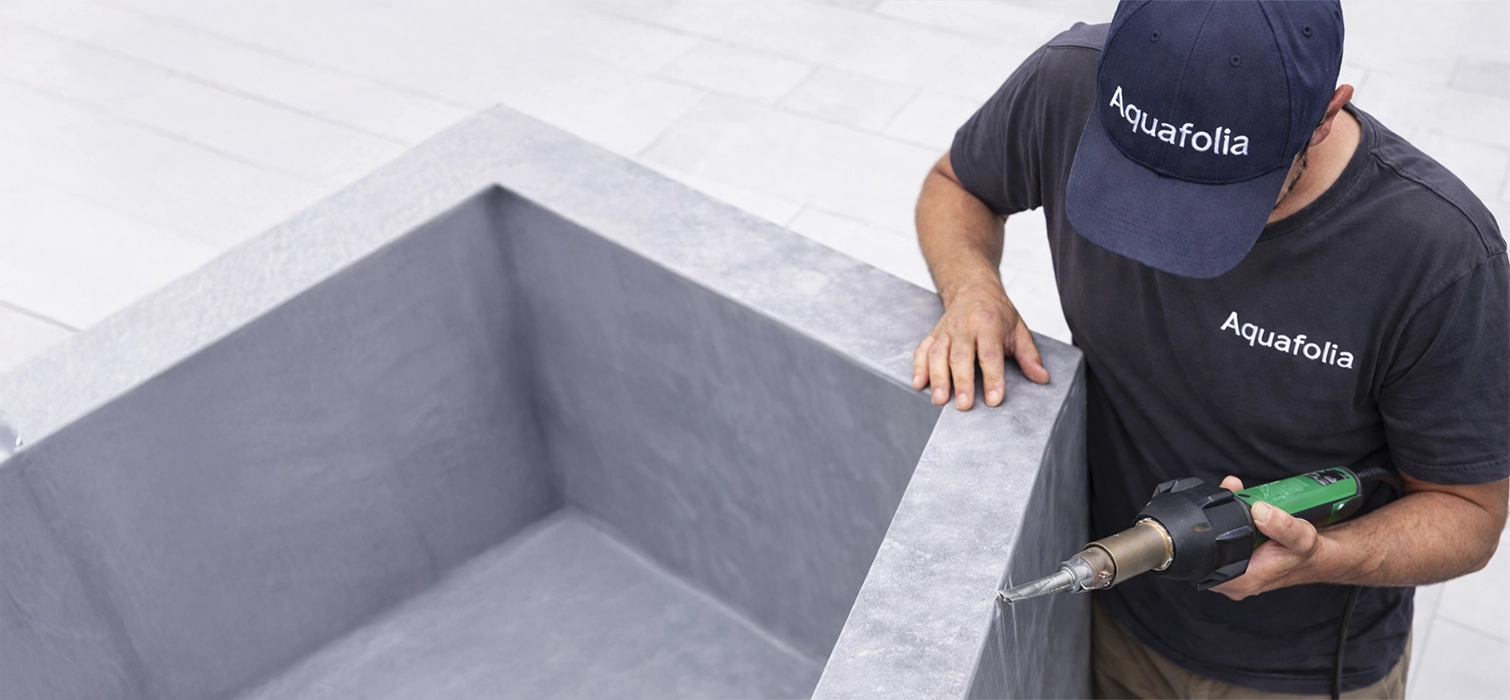 Detailaufnahme einer Aquafolia Poolfolien-Montage mit grauer Poolfolie, präzise Heißluftverschweißung an der Poolkante